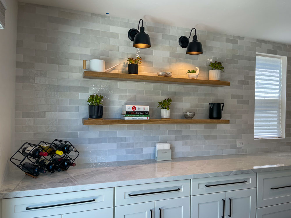 A newly remodeled kitchen with installed tile backsplash, upgraded countertop, and wall-mounted shelves