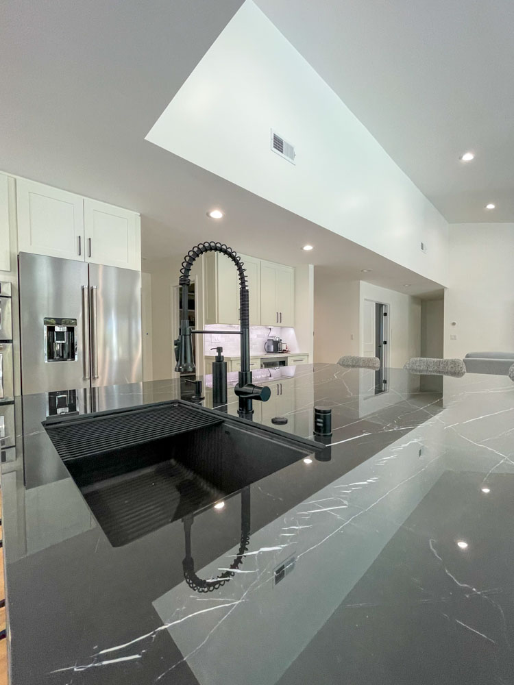 Renovated kitchen with installed Black granite kitchen countertop, sink with adjustable drain feature, and modern faucet