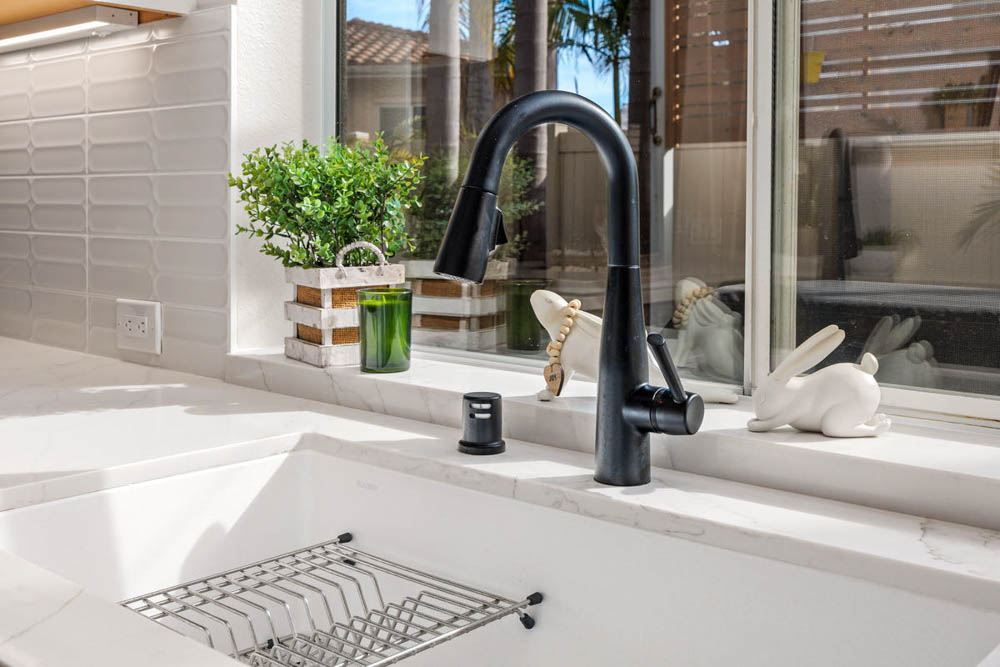 A renovated kitchen with sink on a ceramic countertop and a modern faucet.