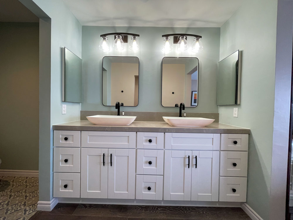 Bathroom storage cabinet with ceramic basin, two mirrors, and wall-mounted lighting fixtures