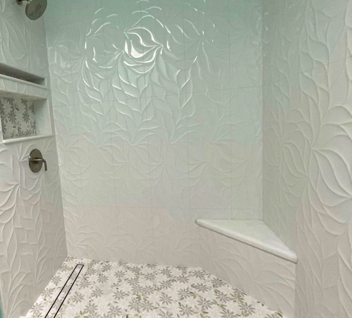Revamped shower area, installed tiles with embossed designs for the backsplash and corner bench, and patterned tile for the floor and niche.