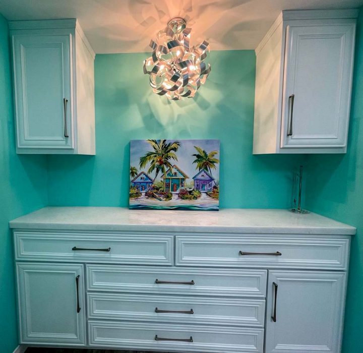 A remodeled bathroom with installed artistic light fixture, ceramic countertop, a tropical painting on top and storage cabinets
