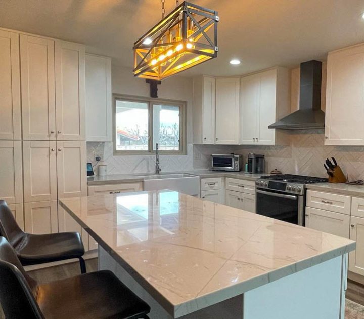 A remodeled kitchen with upgraded countertop, a sink, and repainted cabinets