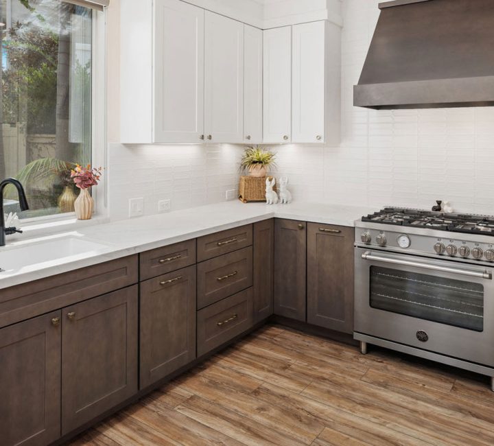 A remodeled kitchen with oak cabinets, exhaust hood, ceramic countertop, sink, and stove oven.